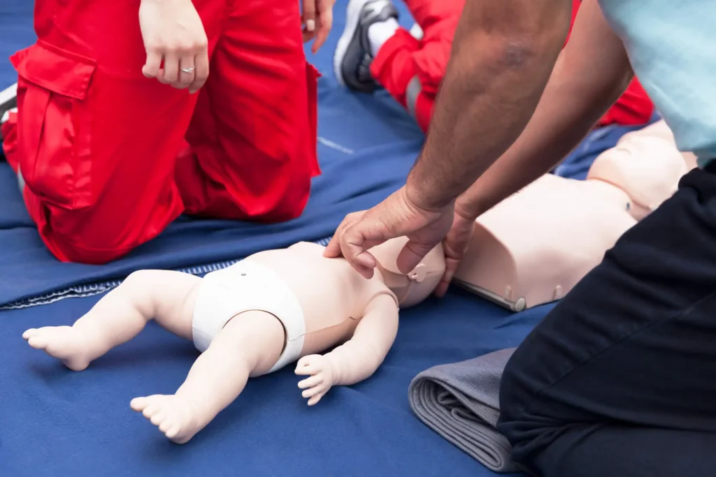 Erste Hilfe Kurse für Säuglinge und Kinder - eine Person wird an der Puppe eines Kindes in Erste Hilfe Maßnahmen eingeschult.